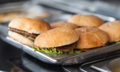 six burgers with lettuce on a pan