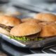 six burgers with lettuce on a pan