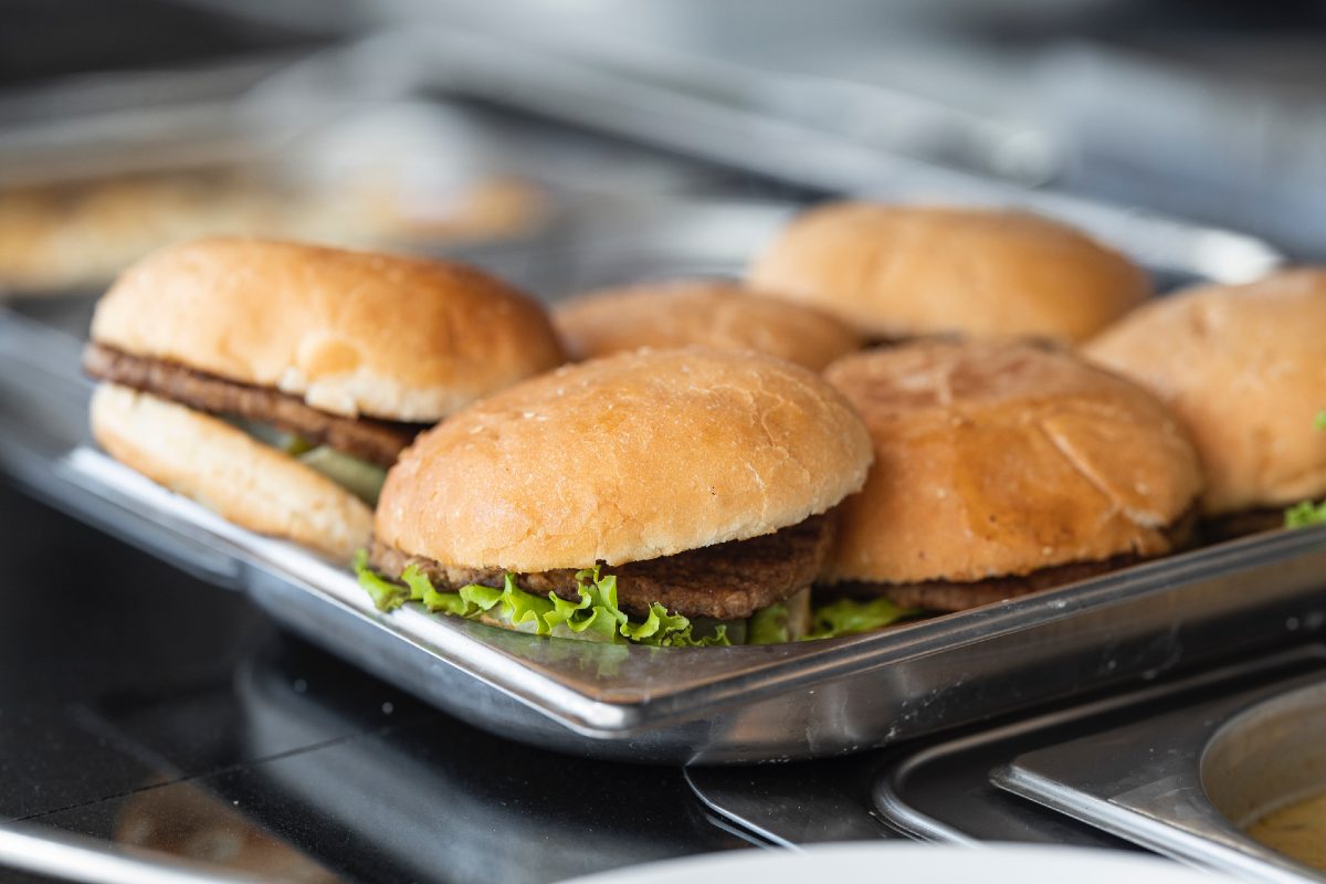 six burgers with lettuce on a pan