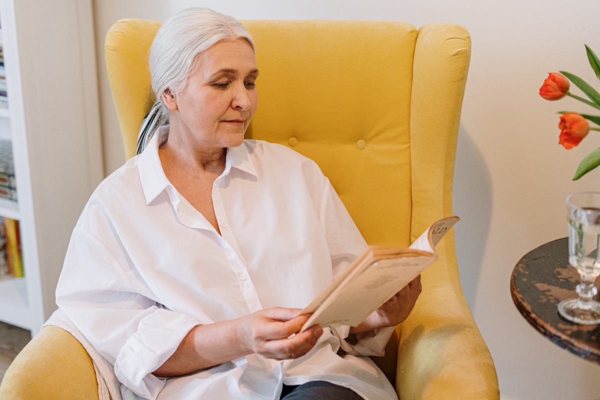 woman reading a book while sitting on a chair