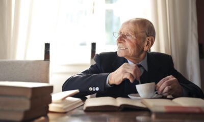 man wearing dark blue suit while holding a tea cup