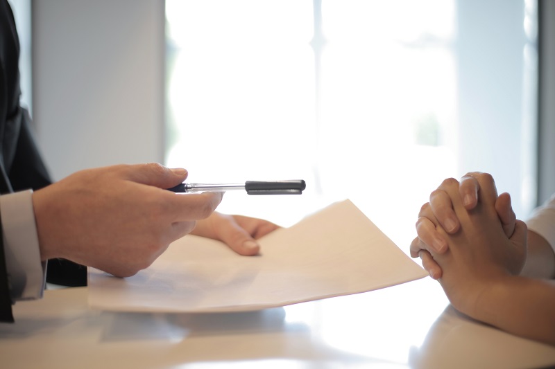 person handing out a pen to another person